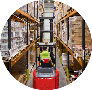 Warehouse worker operating a lifter between stacked boxes, demonstrating efficient warehouse fulfillment operations at Future Pro Logistics