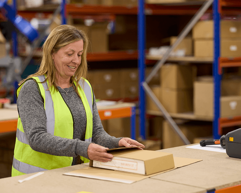 Woman inspecting a shipping box, representing quality control in an Amazon fulfilment centre in the UK